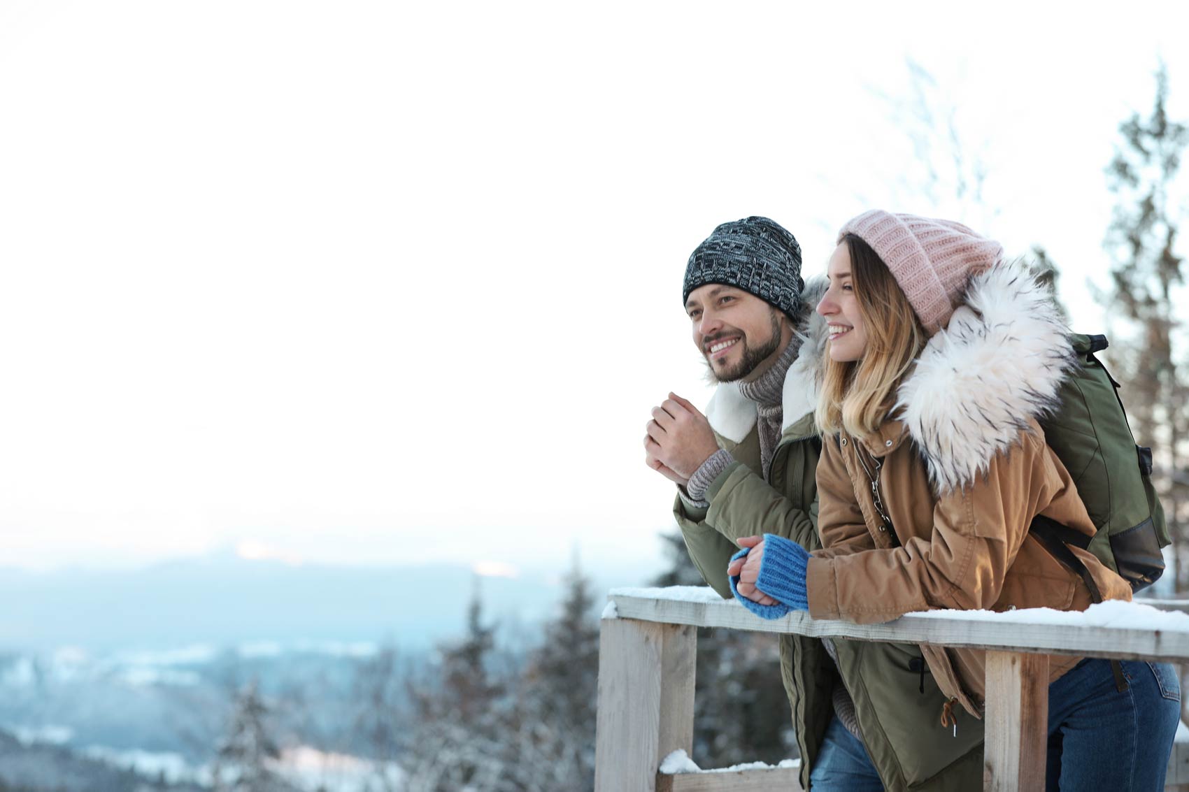 Photo: Couple watching the snowed mountains from a balcony